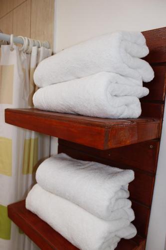 una pila de toallas blancas en un estante del baño en casa saire en San Pedro de Atacama