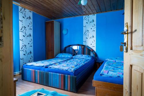 two beds in a room with blue walls at Pensiunea elena in Tăşnad