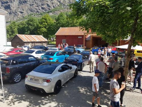 a group of people standing around a parking lot with cars at Lærdalsøren Motor Guesthouse in Lærdalsøyri