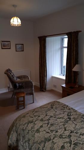a bedroom with a bed and a chair and a window at Achintee Farm Guest House in Fort William