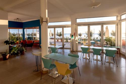 a room with a table and chairs and windows at Hotel Le Trident Thyrsé in Royan