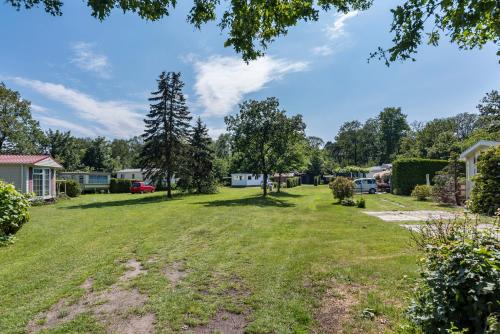 a large yard with trees and houses at Groot hoek Chalet met Airco ,Wasmachine, Vaatwasser,Droger en luxe keuken en zwembad op camping! Immer Besser! in Rijs