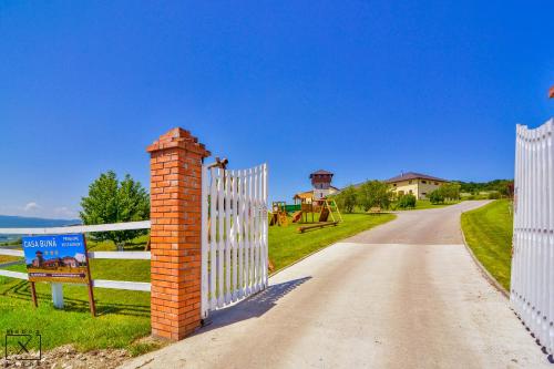 a white fence with a brick pillar next to a road at Pensiunea Casa Buna in Gîrbova