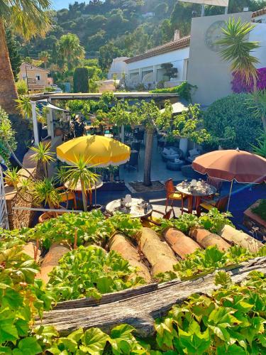 a garden with umbrellas and tables and chairs at Hôtel Beau Soleil in Le Lavandou