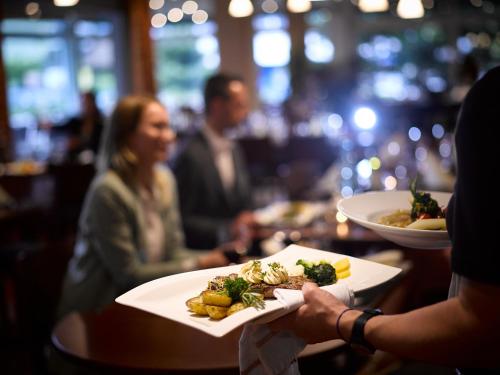 a person holding a plate of food on a table at Hotel Holiday Thun in Thun