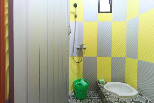 a bathroom with a toilet and a green bucket at Villa Ana in Pasuruan