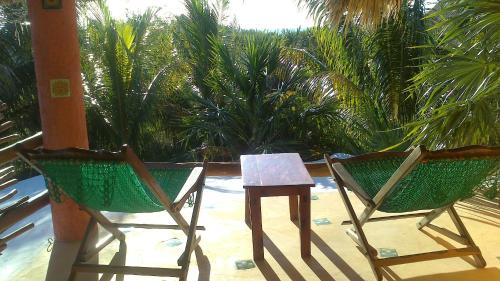 two chairs and a table on a patio with palm trees at Casa Cereza in Holbox Island
