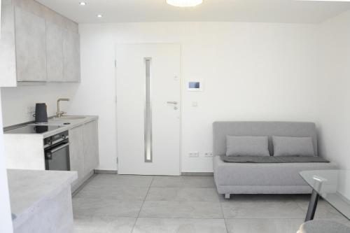 a white kitchen with a couch in a room at Kleine Studio-Wohnung, kontaktloser Check-in in Meckenbeuren