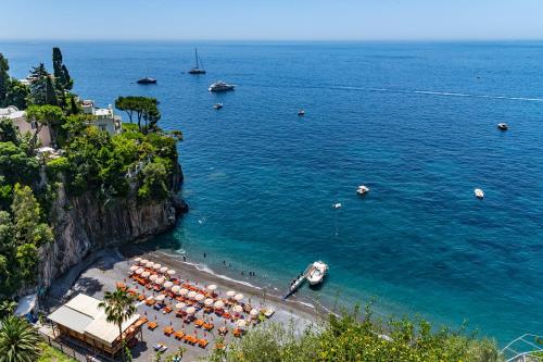 a beach with umbrellas and boats in the water at Villa Nina in Positano