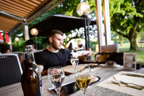 a man sitting at a table with glasses of wine at Hotel Holiday Thun in Thun