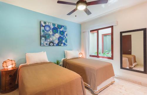 a bedroom with two beds and a ceiling fan at Maya Villa Condo Hotel and Beachclub in Playa del Carmen