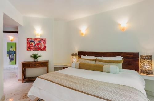 a bedroom with a large white bed and a table at Maya Villa Condo Hotel and Beachclub in Playa del Carmen