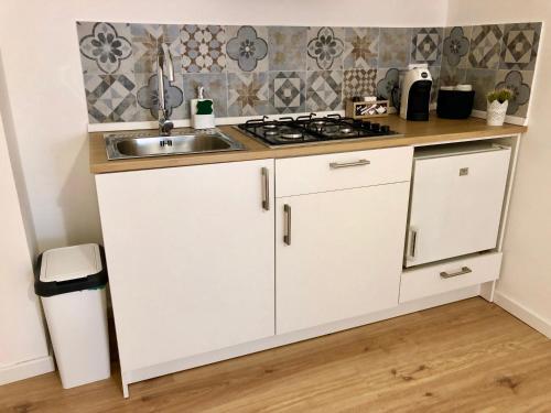 a kitchen with white cabinets and a sink at Mondello Beach Rooms - by the sea in Mondello