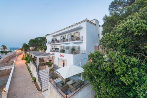 - une vue sur un bâtiment blanc avec un parasol dans l'établissement Boutique Hotel Oriola, à Cala Sant Vicenç