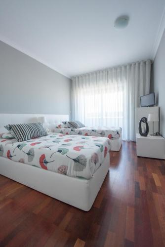 a bedroom with two beds and a wooden floor at Apartamento Mouzinho de Albuquerque in Matosinhos