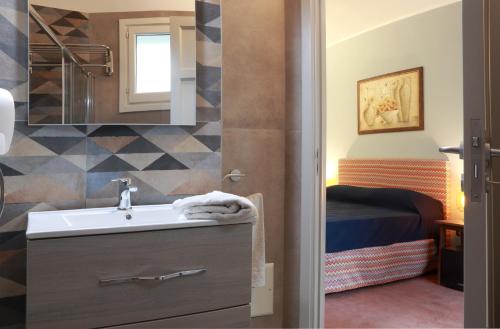 a bathroom with a sink and a bedroom with a bed at Dimora Villa Serena Porto Selvaggio in Santa Caterina di Nardò