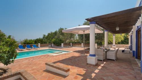 a patio with an umbrella and a swimming pool at Casinhas Wheelchair friendly in Boliqueime