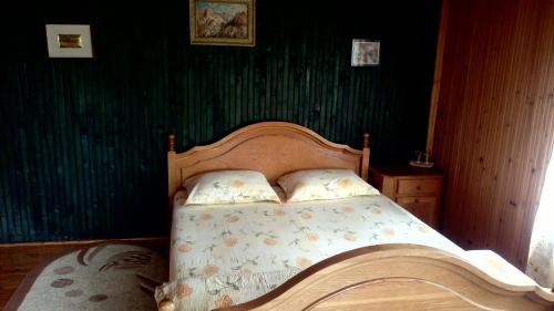 a bed in a bedroom with a green wall at pensiunea Gabriela in Durau