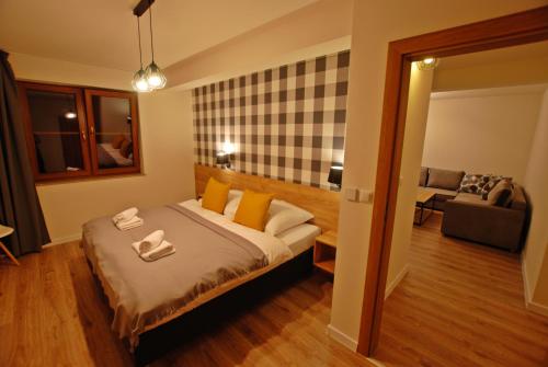 a bedroom with a bed and a living room at Apartamenty Magia Gór in Szczawnica