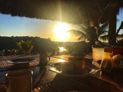un tavolo con un piatto di cibo e il tramonto di Pousada Lua Cheia Caraíva a Caraíva