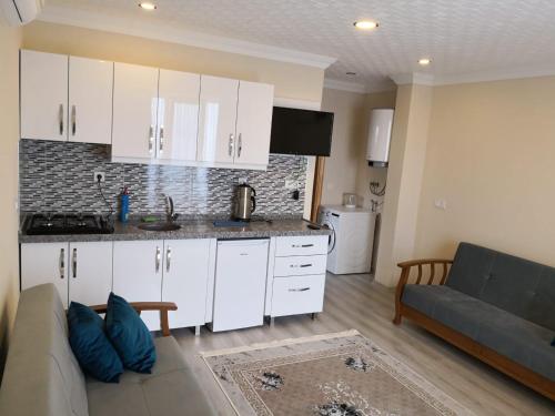 a kitchen with white cabinets and a couch in a living room at Glisura Apart in Uzungol