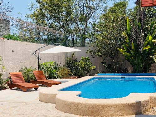 a swimming pool in a yard with two chairs at Casa Balam in Rincon de Guayabitos