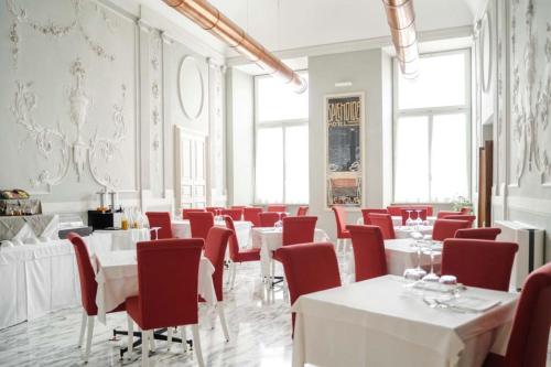 a dining room with white tables and red chairs at Hotel De Ville in Genova