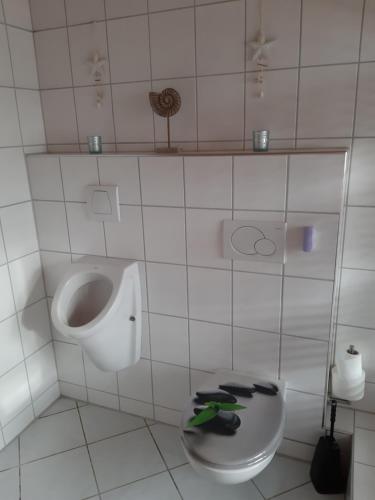 a white bathroom with a urinal and a toilet at Ferienwohnung Heck in Waldeck