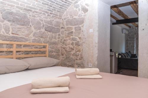 a bed in a room with a stone wall at Apartmani Španja in Vodice