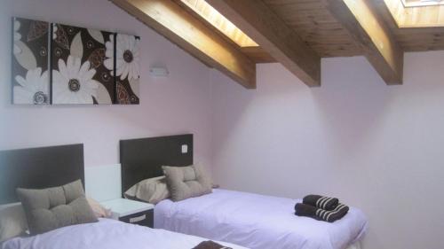 two beds in a room with white walls and wooden ceilings at Los Barruecos in Pinilla de los Barruecos