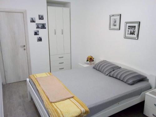a white bedroom with a bed and a cabinet at Tara Deluxe Apartment in Budva