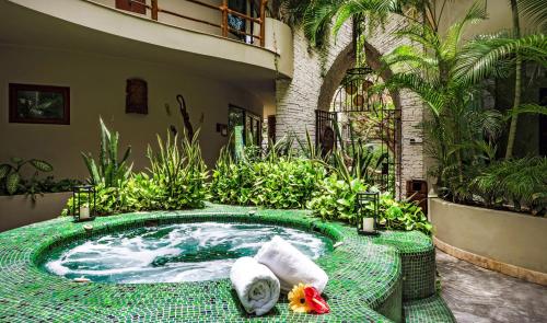 a hot tub in a garden with towels and plants at Maya Villa Condo Hotel and Beachclub in Playa del Carmen