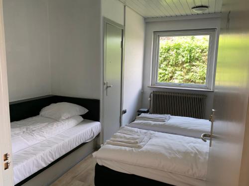 2 camas en una habitación pequeña con ventana en Motel oasen, en Roskilde