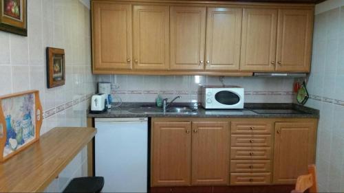a kitchen with wooden cabinets and a sink and a microwave at Country House Alfarim in Alfarim