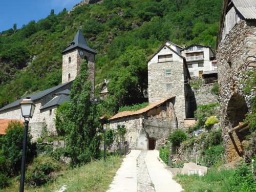 a stone building with a clock tower on a hill at Hostal Casa Laplaza in San Juan de Plan