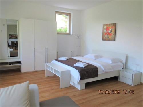 a white bedroom with a bed and a mirror at Sunlight Apartment in Bled