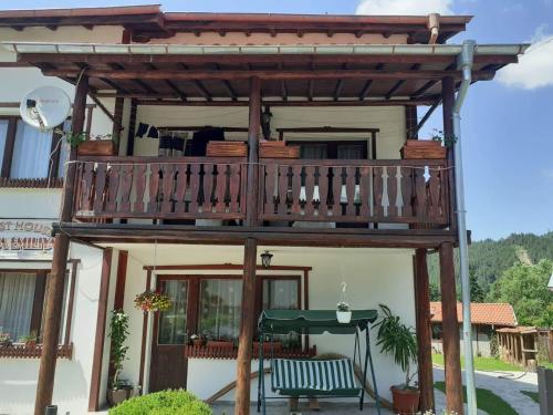 una terraza de madera con una mesa frente a una casa en Mama Emiliya Guest House, en Beli Iskar