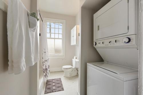 a white bathroom with a toilet and a window at Freret Apartments near Streetcar & Tulane in New Orleans
