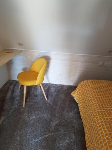 une chaise jaune dans une chambre avec un lit dans l'établissement Angers Green Lodge - Yellow Sun Appartement, à Angers