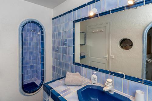 a blue tiled bathroom with a sink and a mirror at Maison Carles BnB in La Colle-sur-Loup