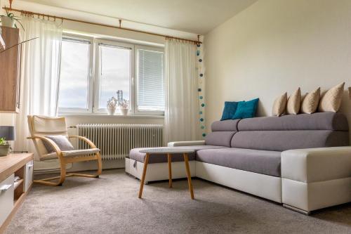 a bedroom with a bed and a chair and a window at Apartman Breza in Vysoké Tatry