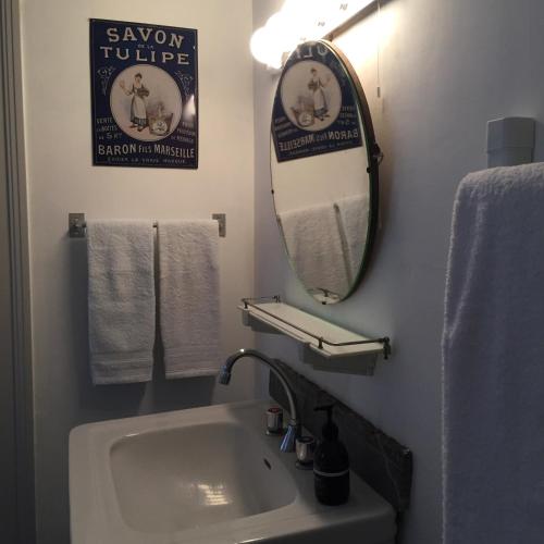 a bathroom with a sink and a mirror and towels at La Grenouille Noire in Marcillat-en-Combraille