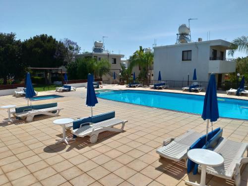 a pool with chairs and tables and umbrellas at Constantaras Apartments in Protaras