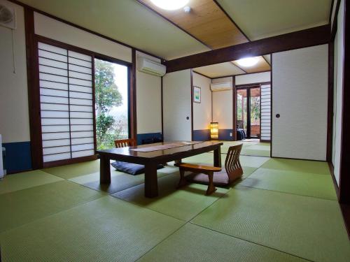 a dining room with a table and chairs and windows at Yufuin-Sanso Waremokou in Yufuin