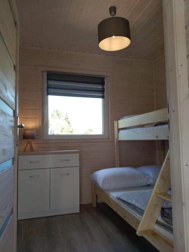 a small room with a bunk bed and a window at Domki na górce in Kołczewo