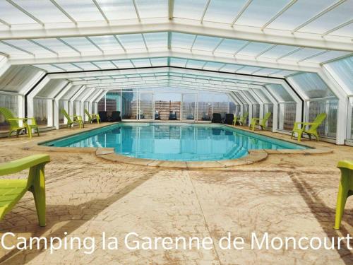 - une piscine dans un bâtiment avec des chaises vertes dans l'établissement Camping La Garenne De Moncourt, à Rue