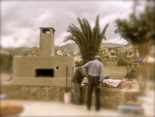 two men are standing next to a brick oven at Sarikampos Beach in Myrtos