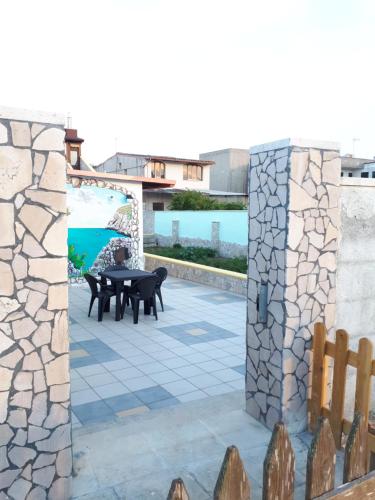 a patio with a table and chairs and a stone wall at Oltremare in Vignacastrisi