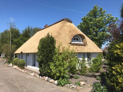 a thatch roofed house with a window at Refugium im Nordseewind in Norddeich