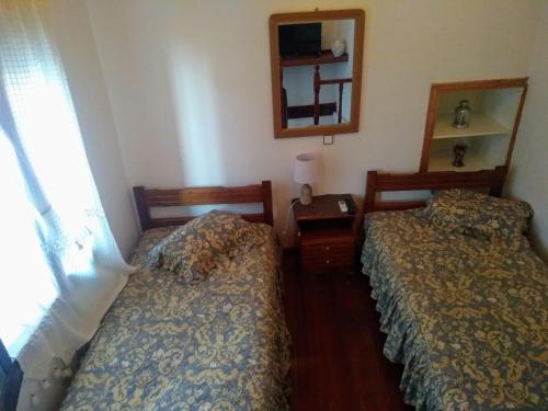 two beds in a small room with a mirror and a window at Dameli in Sykaminéa